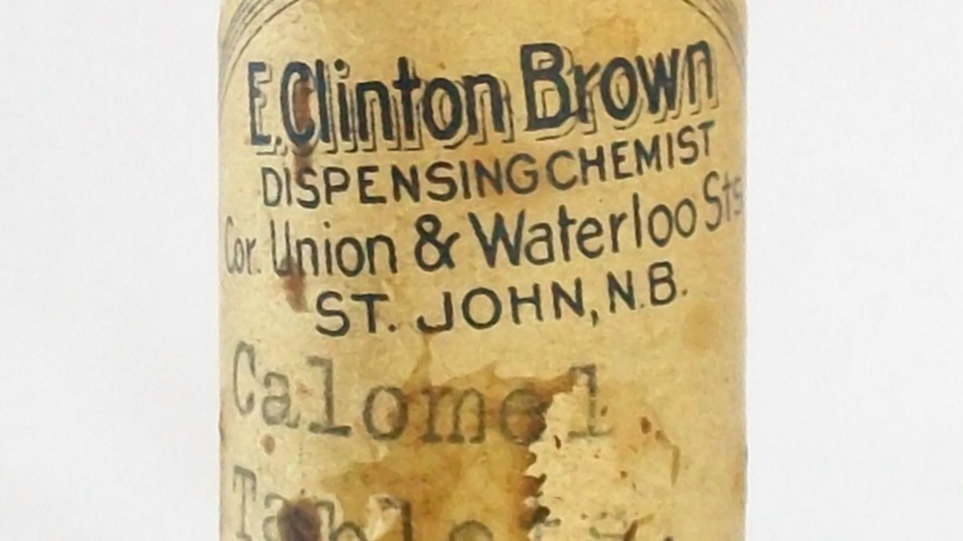 A small, old, empty glass bottle with a cork in it. A worn lable on the bottle states that the bottle contains calomel tablets. The chemist's name is printed on the label: Clinton Brown dispensing chemist, Corner Union & Waterloo St, St. John., N.B. There