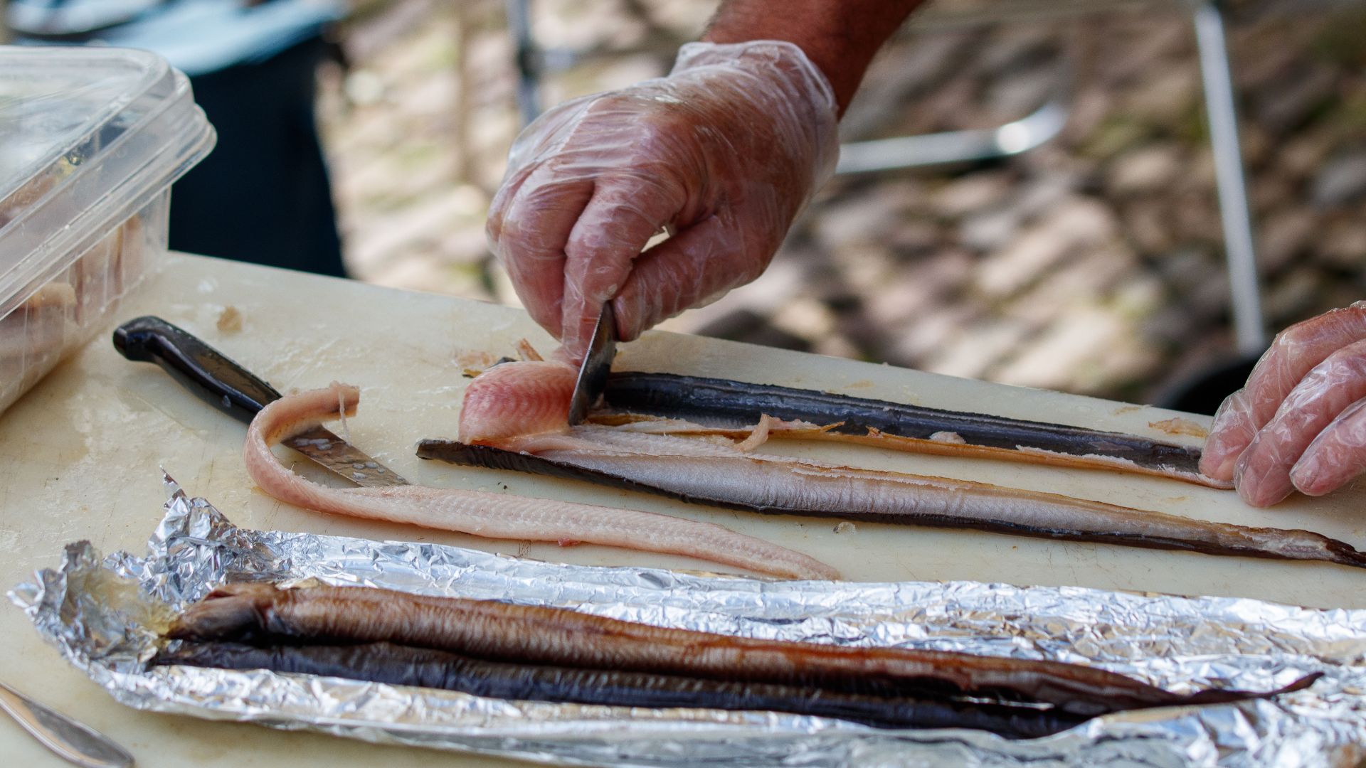 Hands preparing fish fillets outdoors, showcasing culinary skills and fresh ingredients.