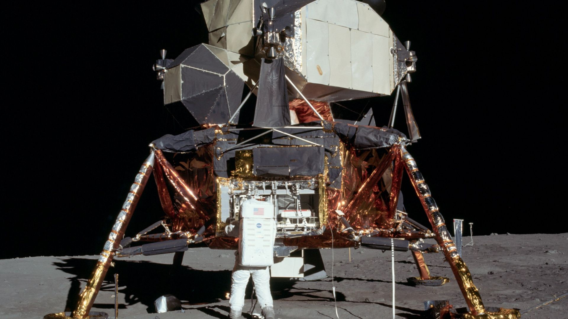 Buzz Aldrin removing the passive seismometer from a compartment in the SEQ bay of the Lunar Lander.