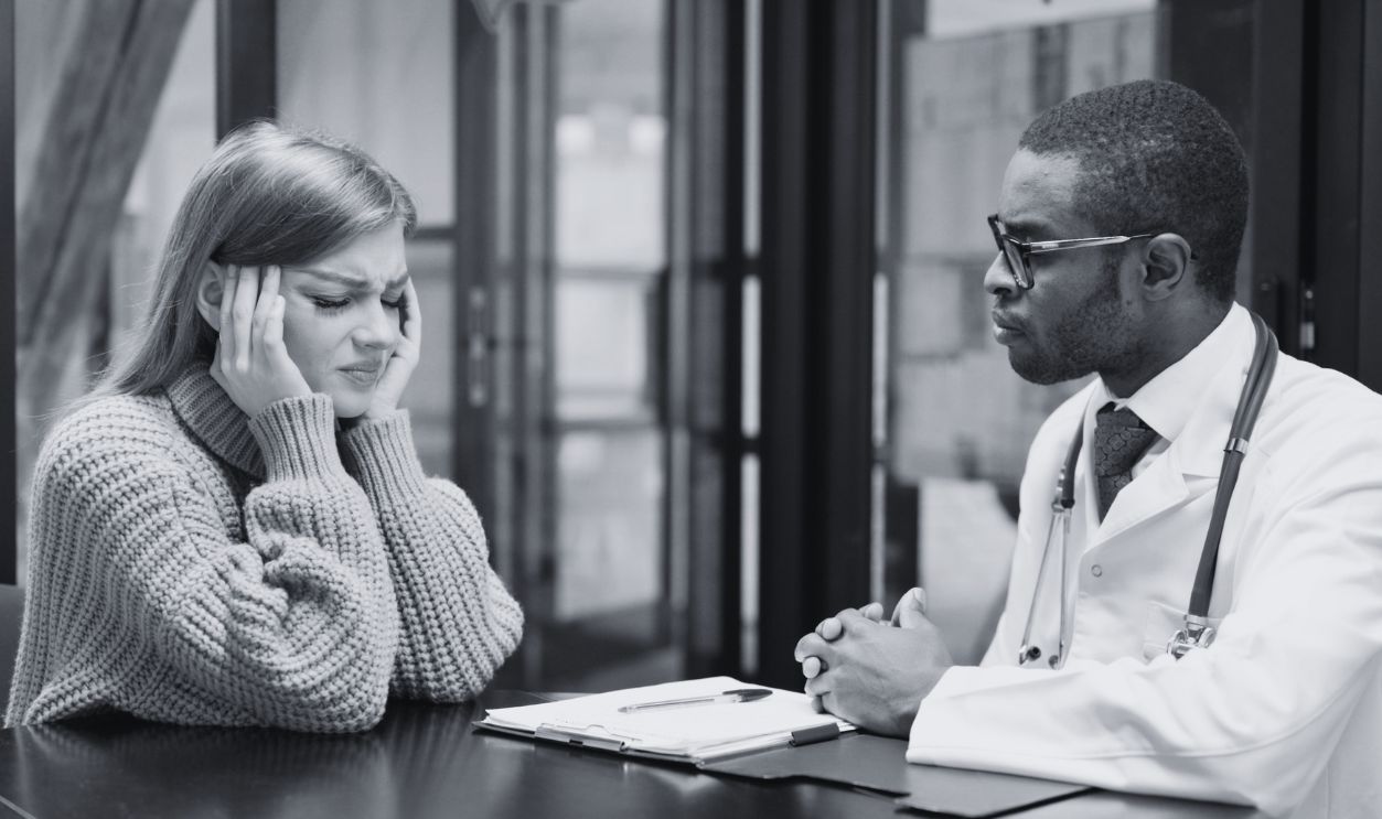 Female Patient with Headache Talking with African Male Doctor