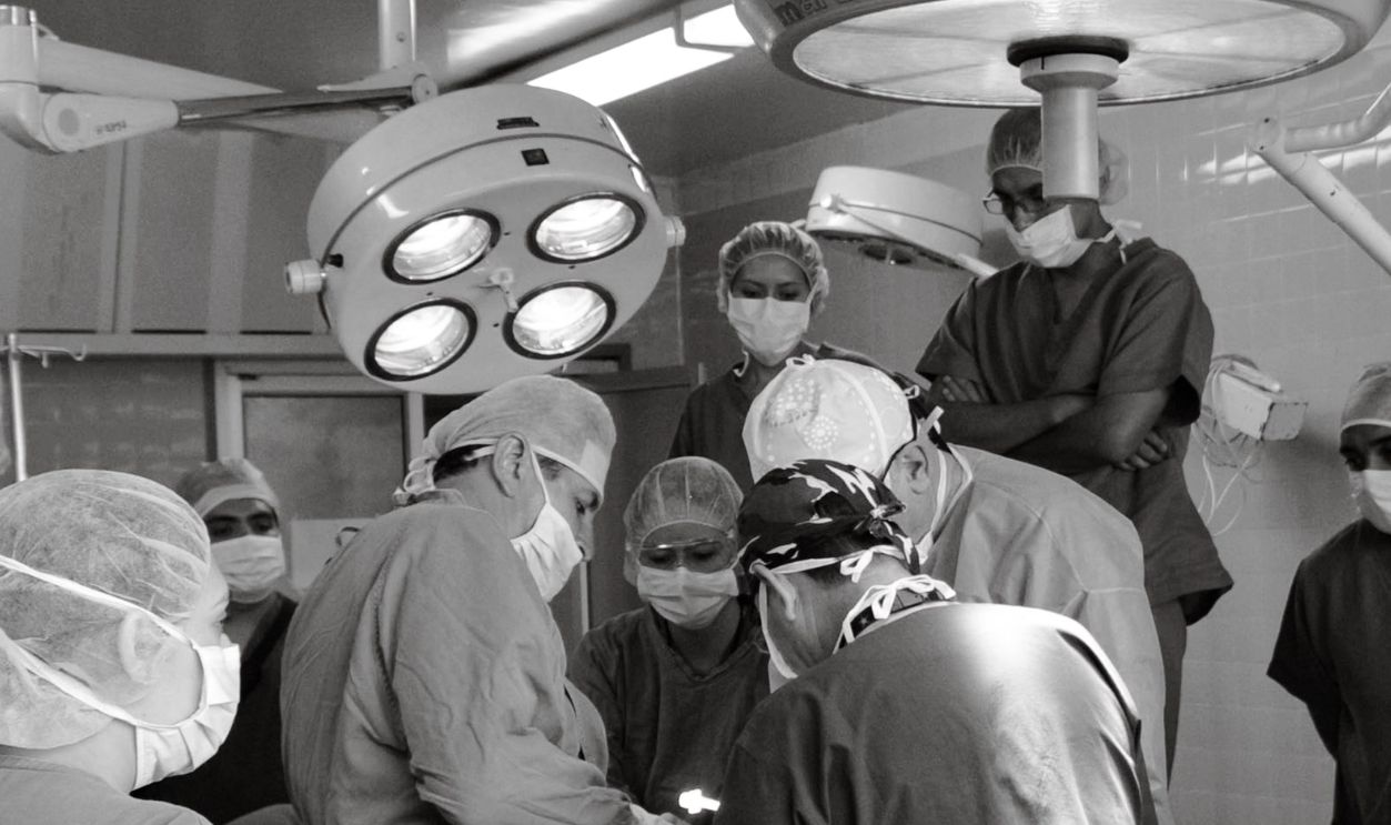 Surgical team performing a medical procedure in a busy operating room. Medical teamwork and precision.