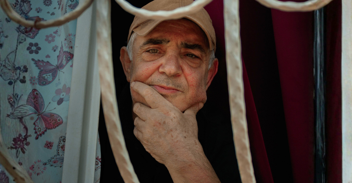 pensive-elderly-man-gazing-through-window-bars
