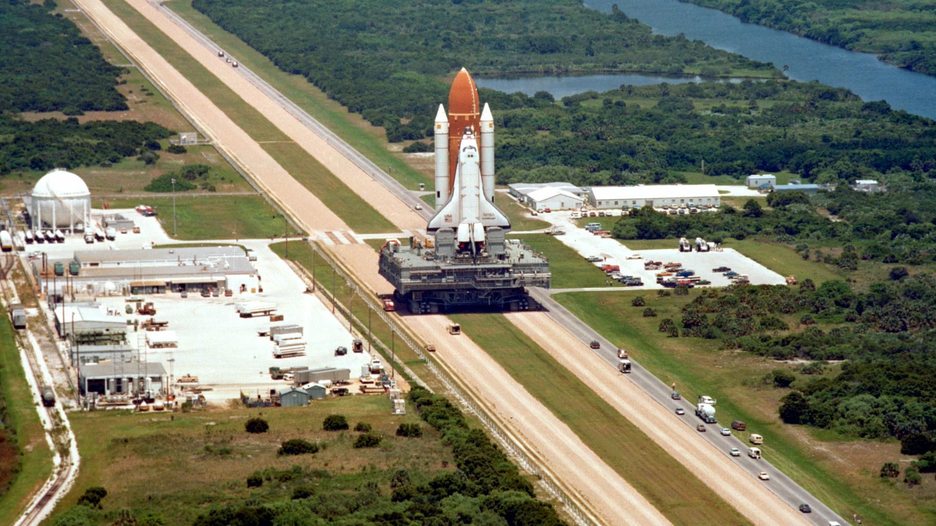 Space Shuttle Challenger is carried by a Crawler-transporter on the way to its launch pad, prior to its final flight before being destroyed in the Space Shuttle Challenger disaster.