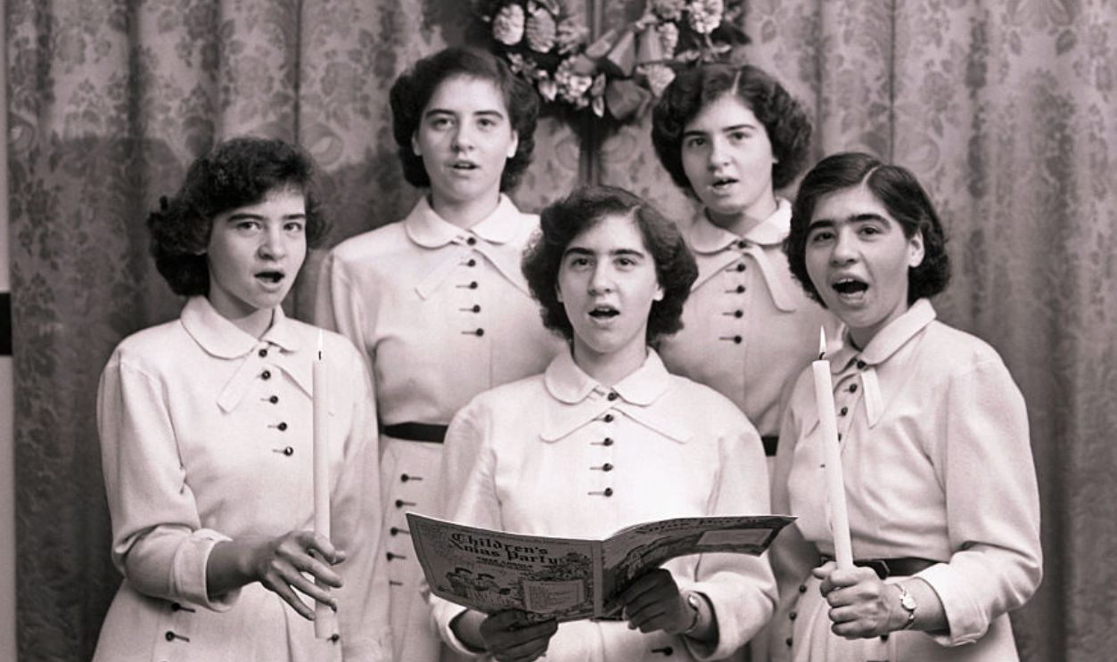 (Original Caption) Christmas Quintet. Nothing so completely exemplifies the spirit of Christmas as the singing of traditional carols. That is why the Dionne Quintuplets, who have always loved to sing, enjoy this season almost morethan any other. For weeks they have practised to assume perfect harmony for their performance on Christmas Day. Her the Quints give up a preview of how they will present a program of carols for their family on Christmas Day. From left to right are Yvonne, Cecile, Marie, Annette and Emilie.