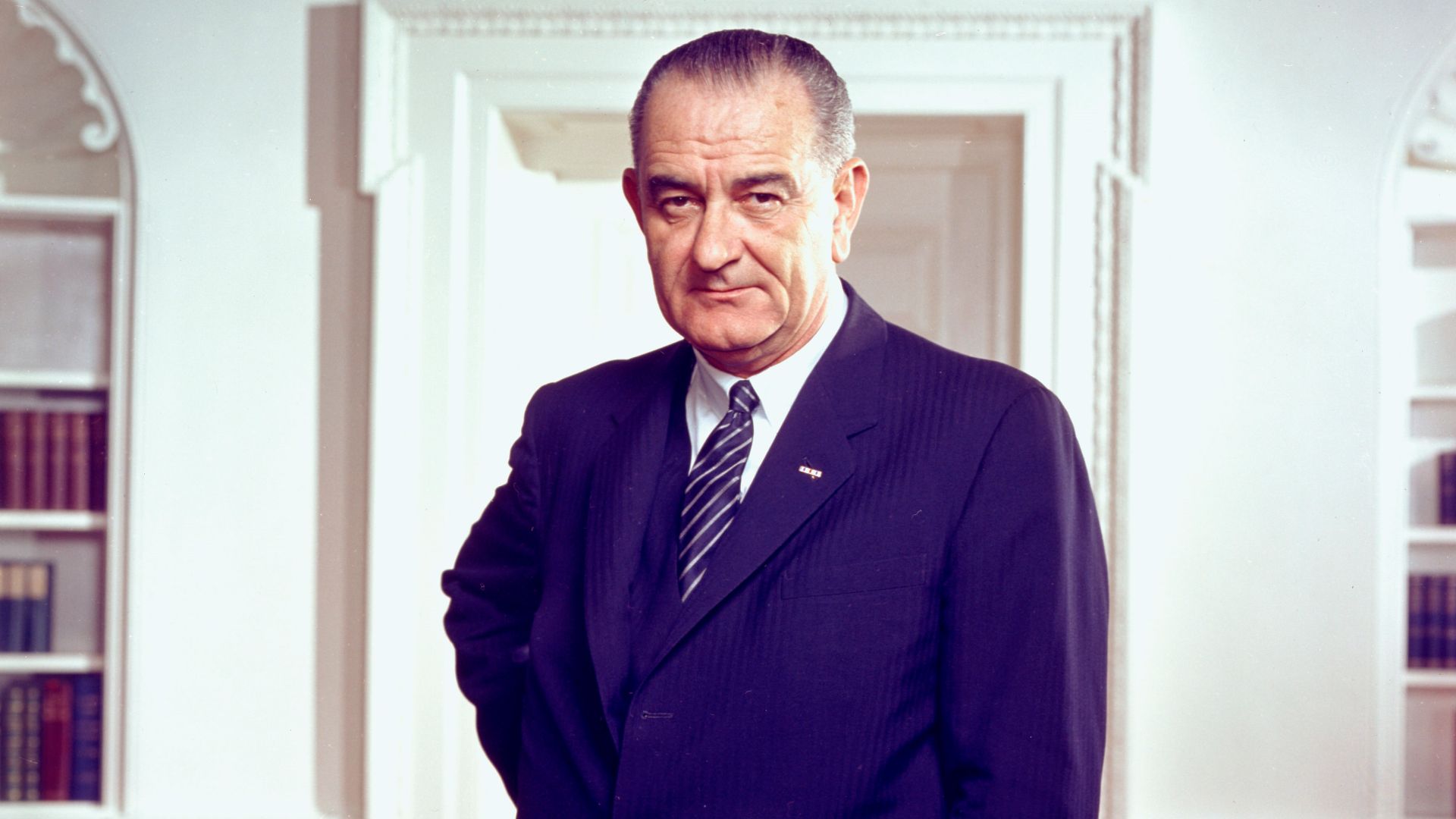 Photo portrait of President Lyndon B. Johnson in the Oval Office, leaning on a chair