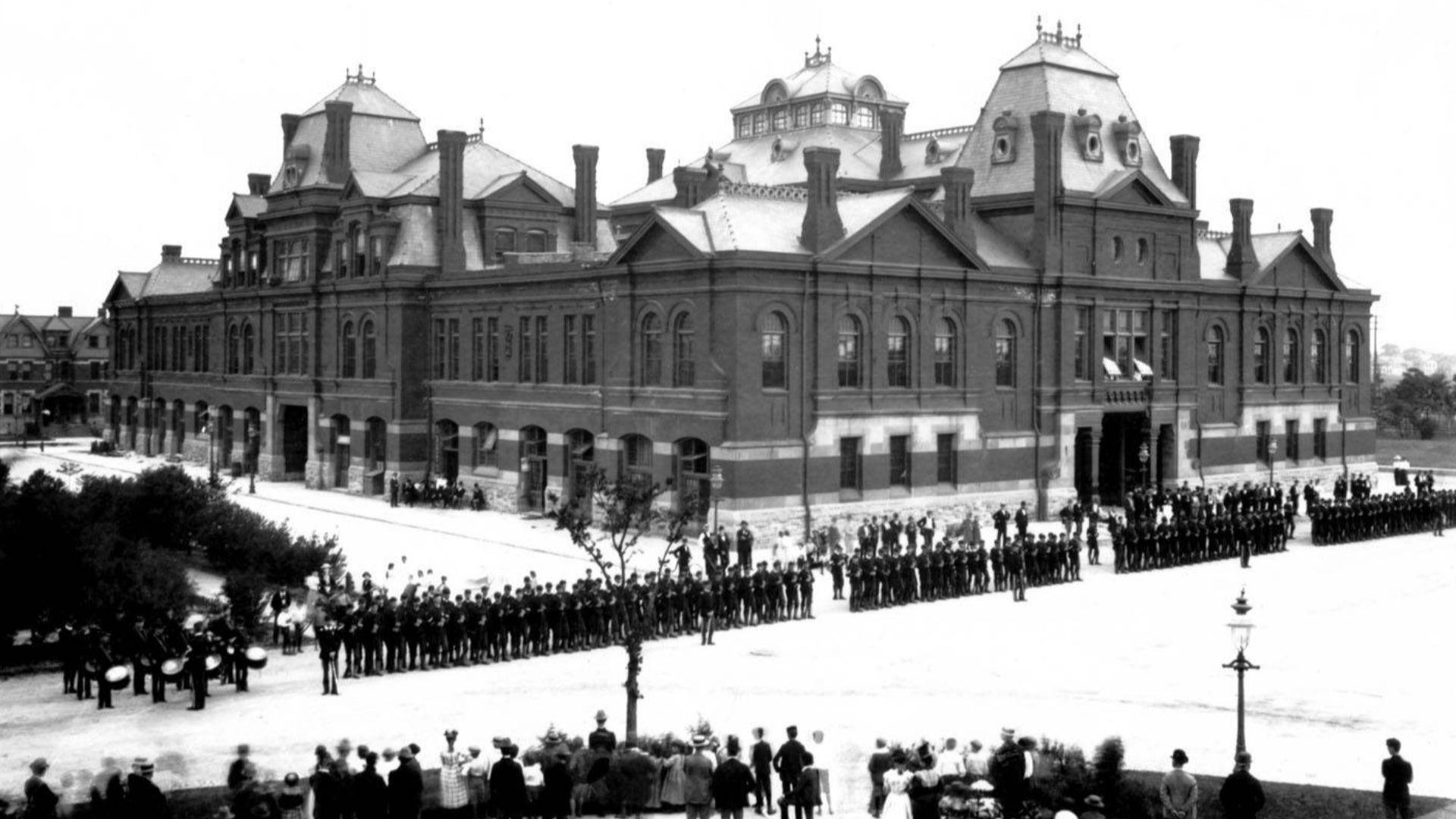 Pullman strikers outside Arcade Building in Pullman, Chicago. The Illinois National Guard can be seen guarding the building during the Pullman Railroad Strike in 1894. Photographed from the Florence Hotel by the Pullman Company staff