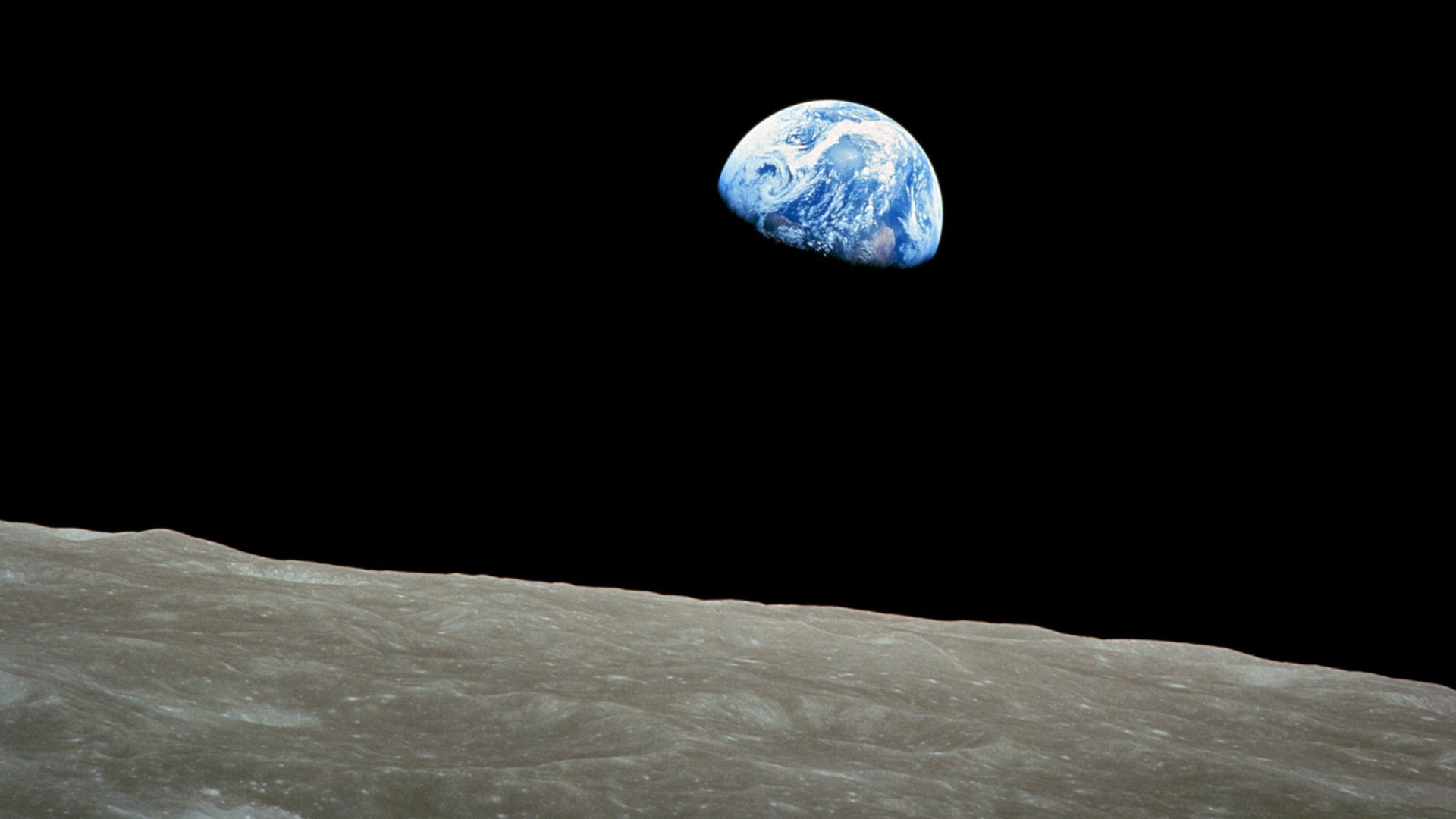 Taken by Apollo 8 crewmember Bill Anders on December 24, 1968, at mission time 075:49:07 [8] (16:40 UTC), while in orbit around the Moon, showing the Earth rising for the third time above the lunar horizon. The lunar horizon is approximately 780 kilometer