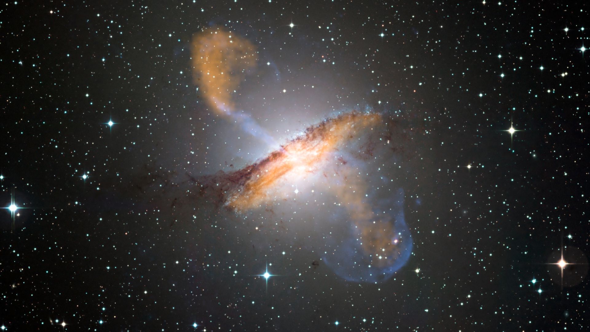 Colour composite image of Centaurus A, revealing the lobes and jets emanating from the active galaxy’s central black hole. This is a composite of images obtained with three instruments, operating at very different wavelengths. The 870-micron submillimetre