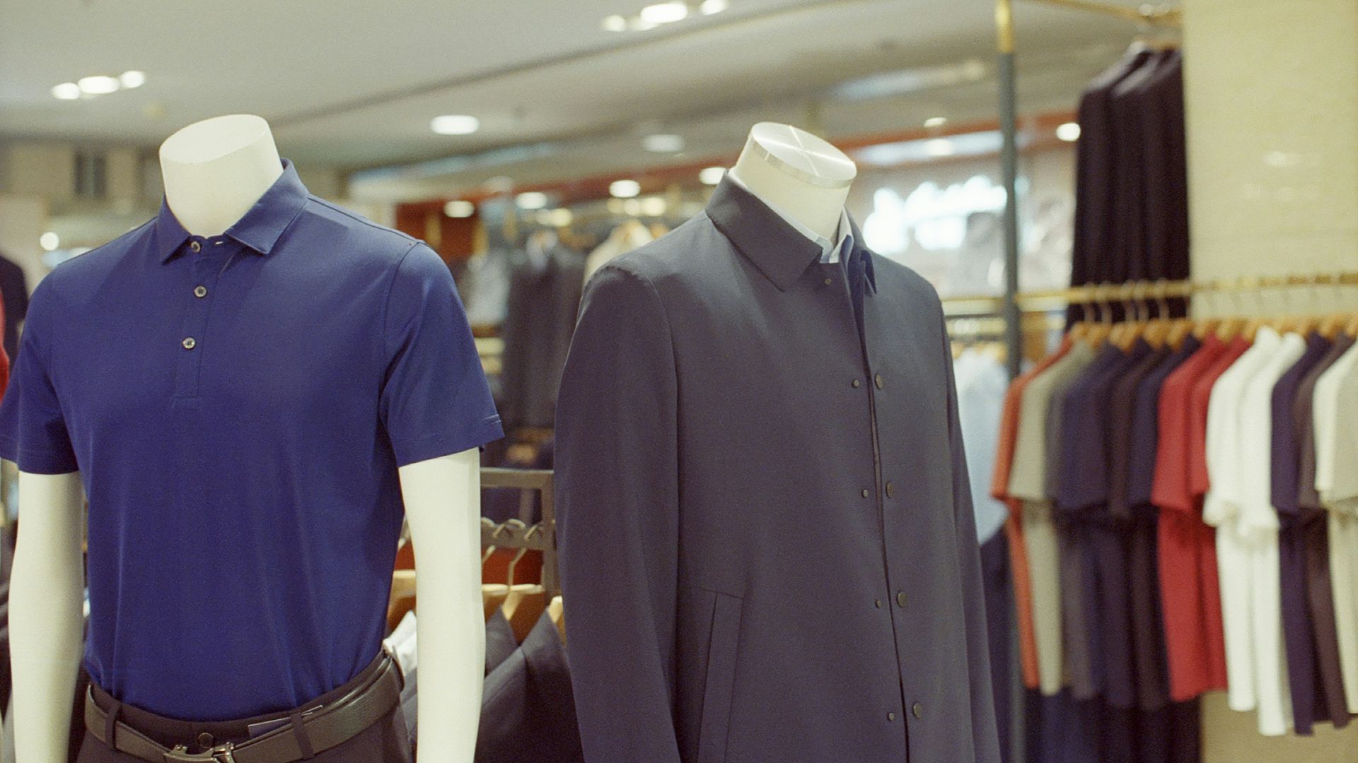 Two mannequins display men's clothing in a store