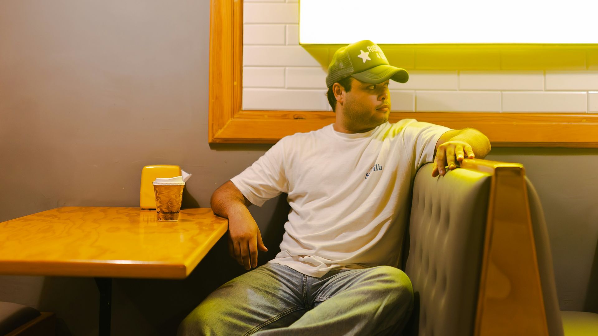 Man in baseball cap sits in booth at diner