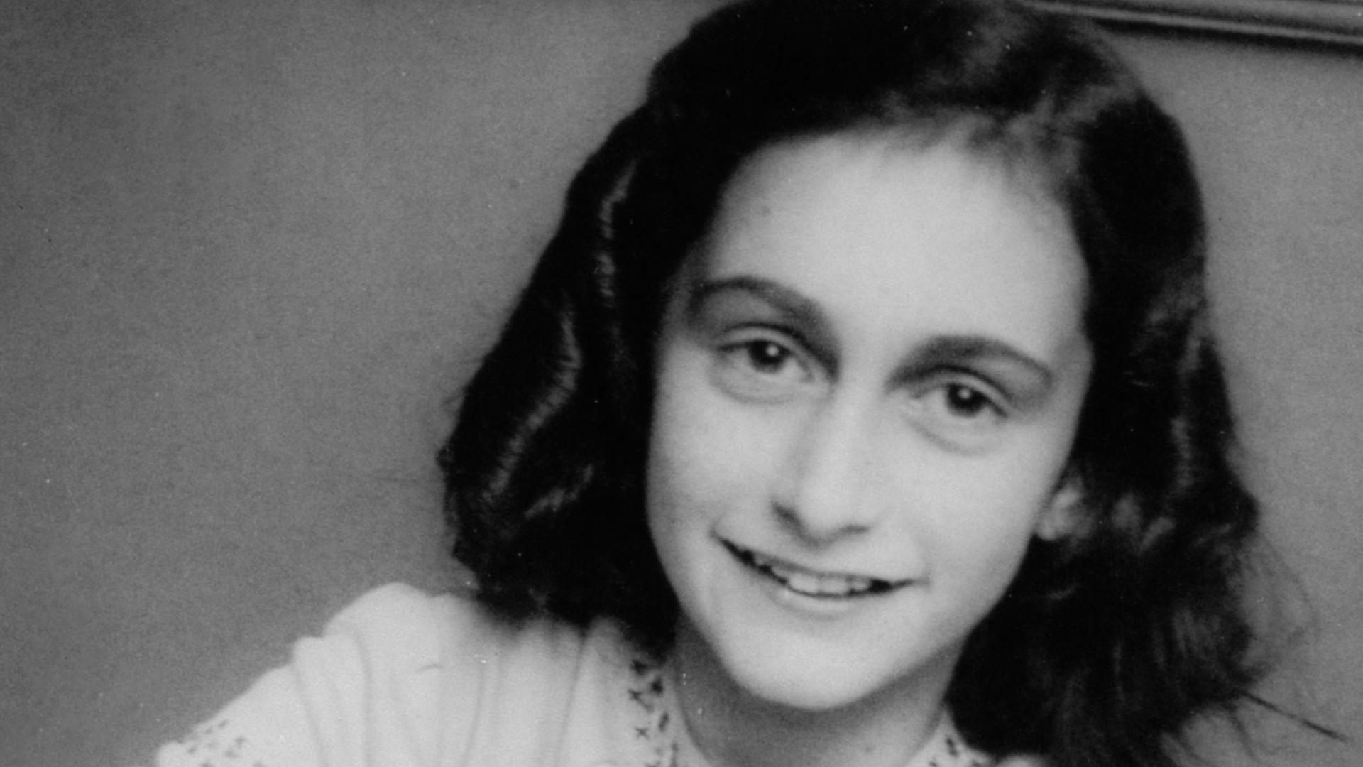 Anne Frank laughing at the school photographer. This photograph was made at the Joods Lyceum (Jewish High School Amsterdam, address Voormalige Stadstimmertuin 1), December 1941.