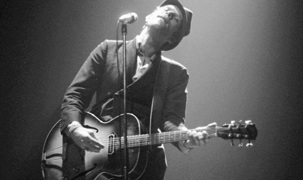 UNITED KINGDOM - MARCH 23: Photo of Tom WAITS; performing live onstage at the Victoria Apollo, playing guitar