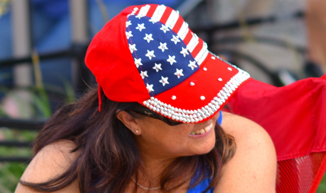 Woman wears American flag-themed attire outdoors, enjoying the event.