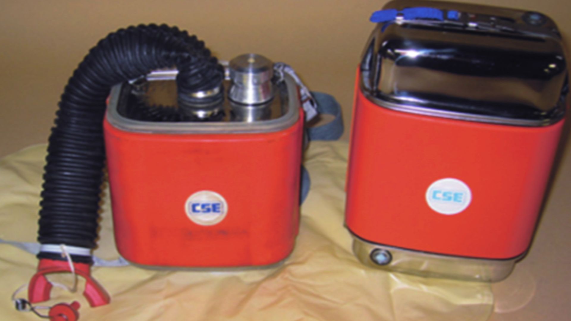 A photo of two CSE Corporation SR-100 self-contained self-rescuer (SCSR) devices in the opened (left) and unopened (right) states. The original photo was retouched by the Wikimedia Commons user Gazebo.