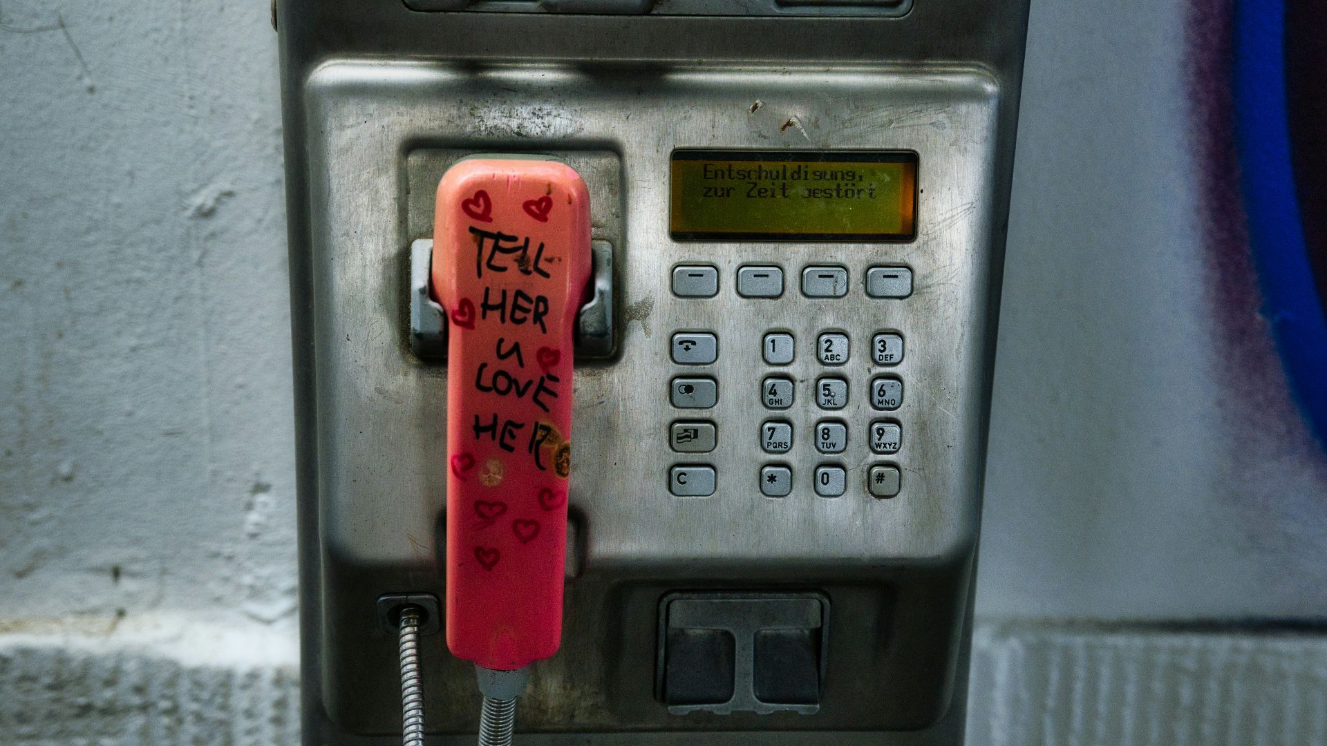 an old pay phone with graffiti on it
