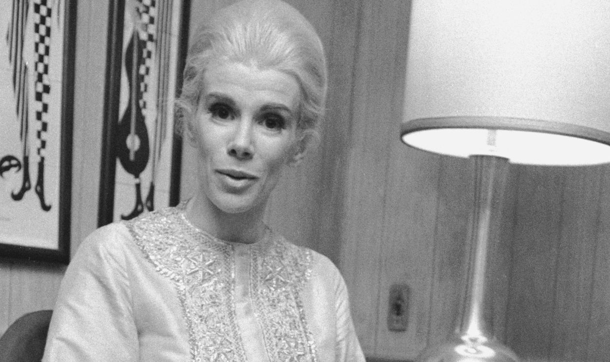 American comedian, actress, and talk show host Joan Rivers sits on a chair as she wears an embroidered kaftan, 1970s.