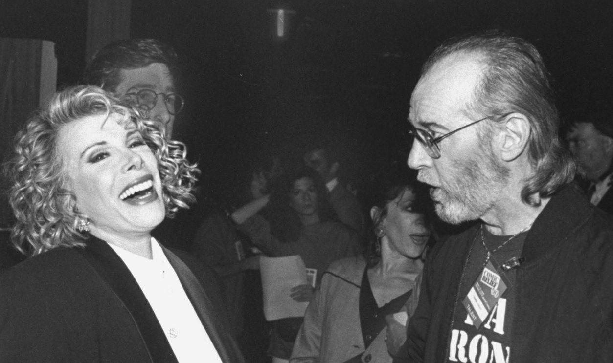 Comedienne Joan Rivers laughing w. comedian George Carlin at party for HBO's Comic Relief IV, a telethon which raises money for the homeless, at Radio City Music Hall.