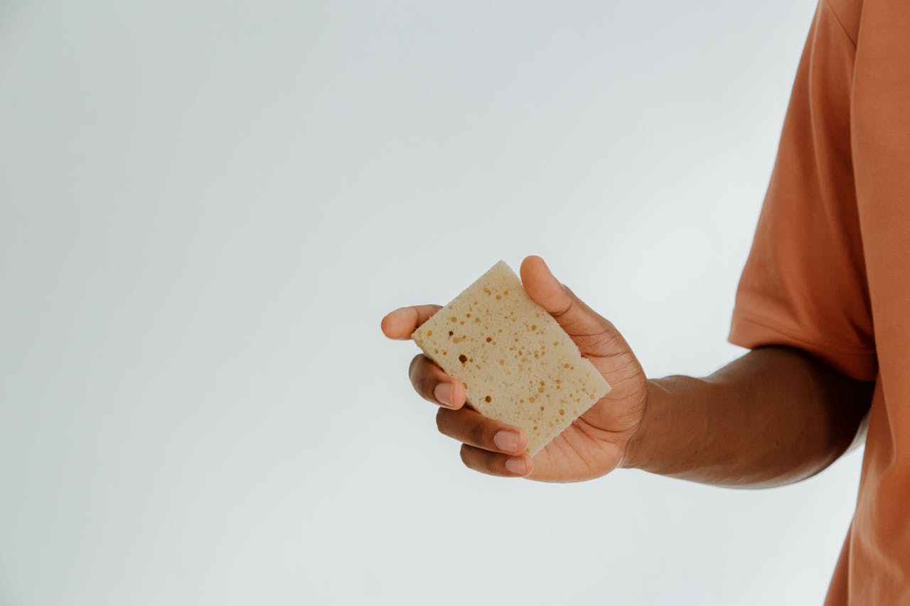 Man holding a sponge in hand.