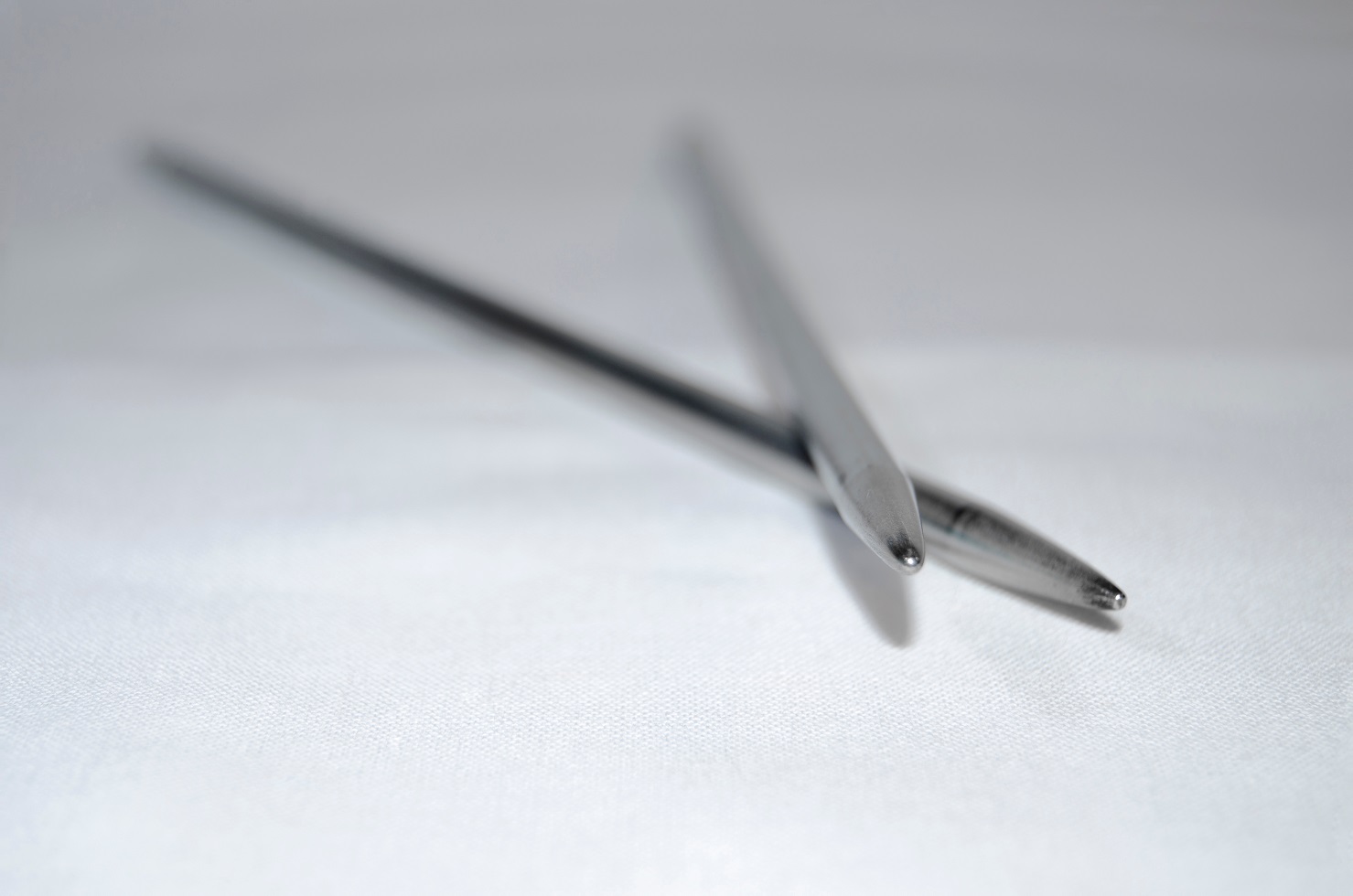 Two knitting needles close-up. Gray background