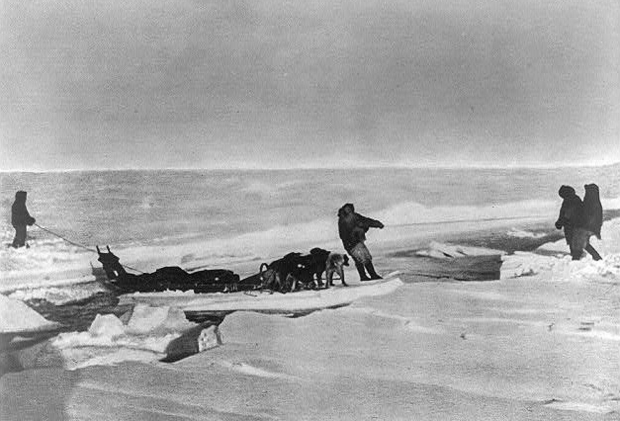 Men and dog sled crossing water on piece of an iceberg - 1909