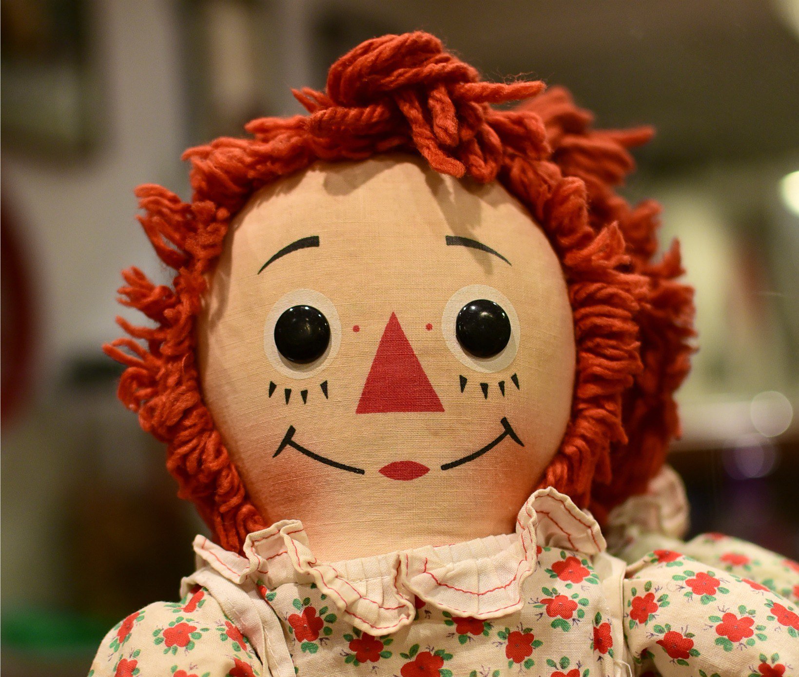 Photo of Raggedy Ann a rag doll with red yarn for hair and has a triangle nose.