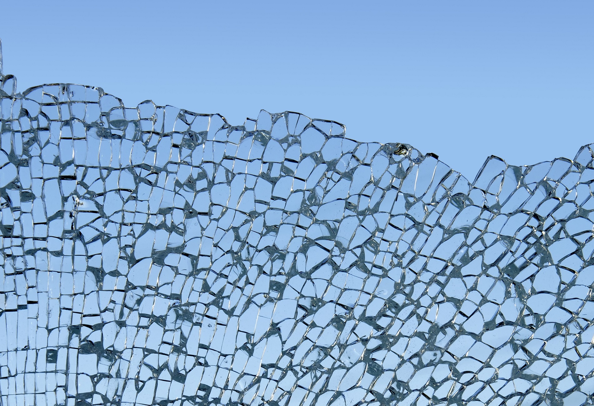 Close-up of shattered tempered glass against the sky