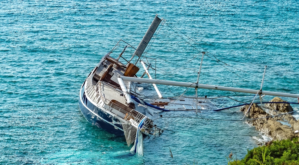 Rocky coast with stranded damaged sailboat