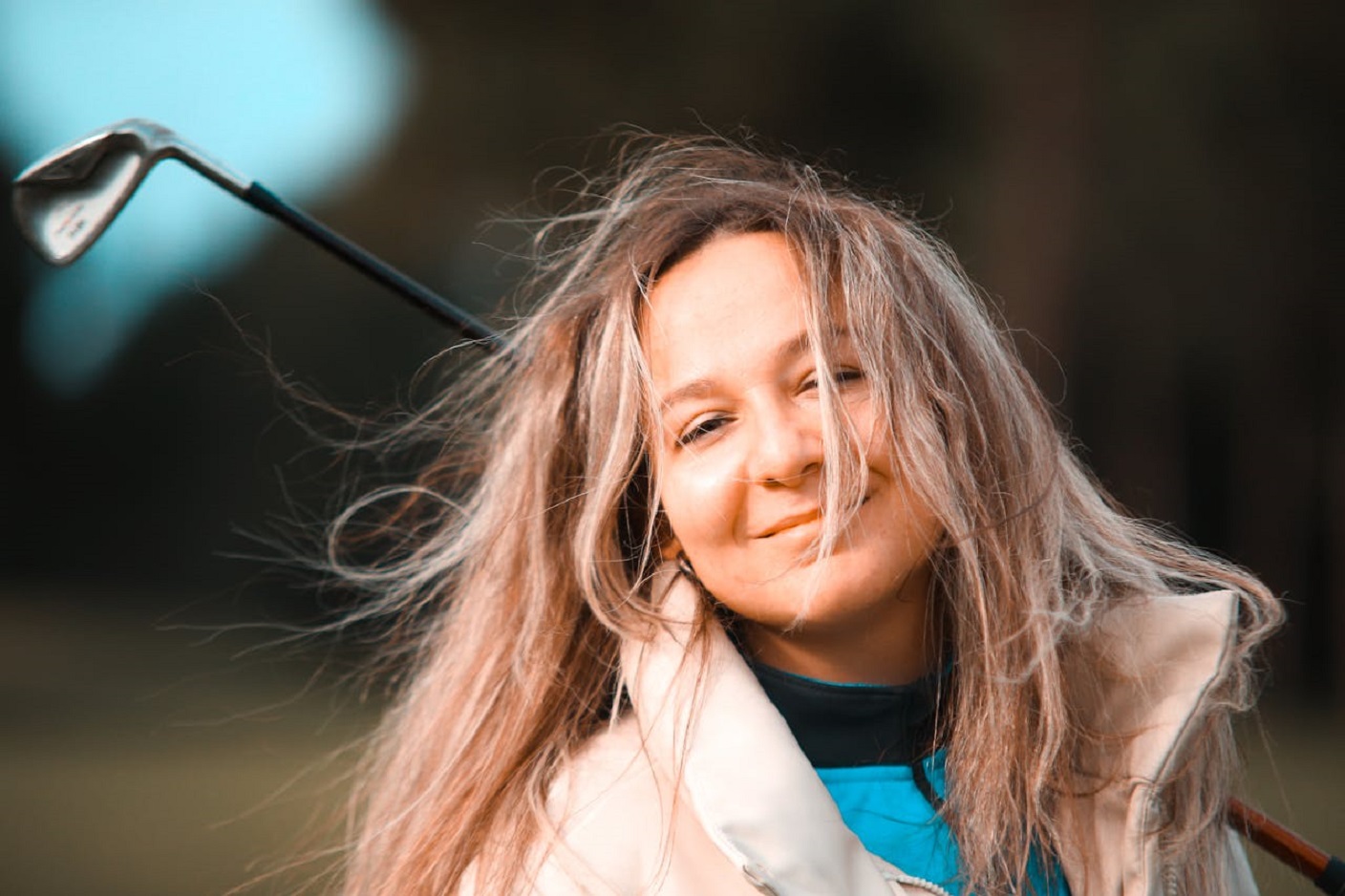 Smiling female holding a golf bat.