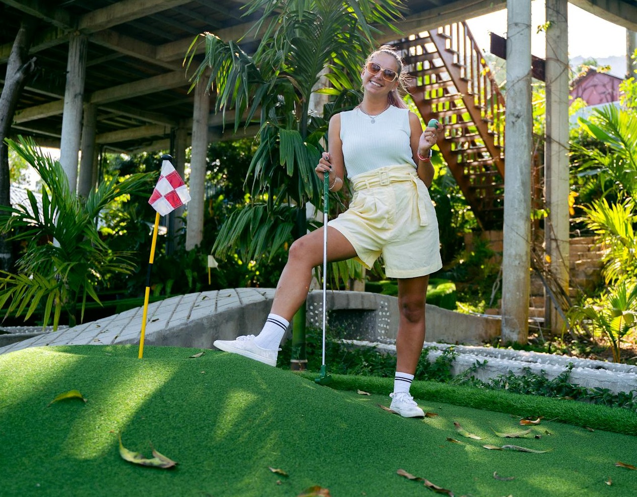 Female mini golfer is smiling at the camera.