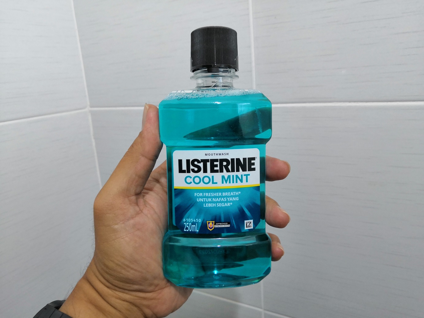 Hand holding a Listerine mouthwash bottles.