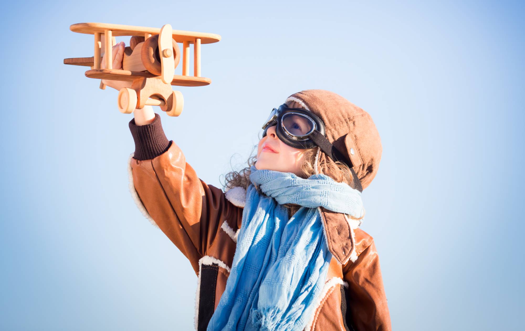 Happy kid playing with toy wooden airplane