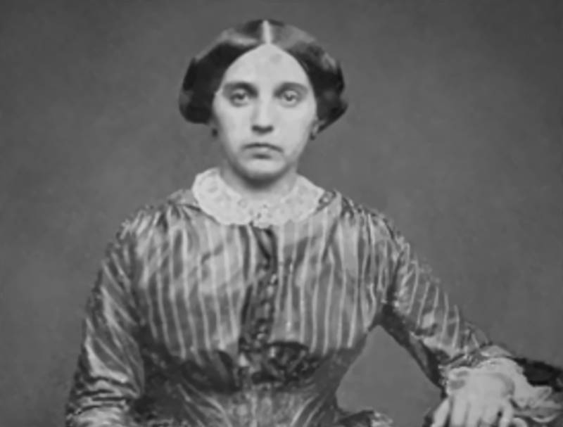 Camila O'Gorman in line print dress looking at camera