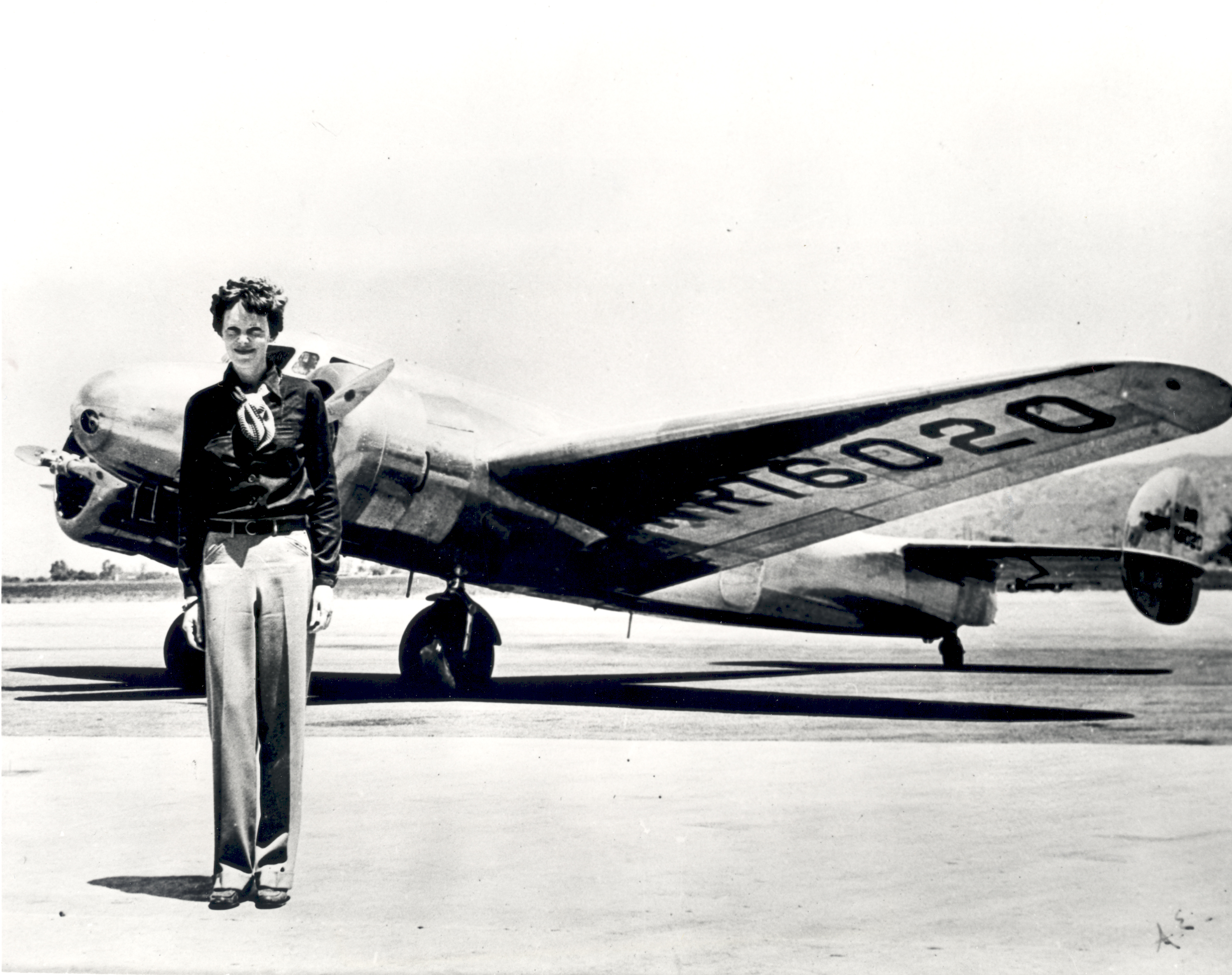 Amelia Earhart standing in front of a plane