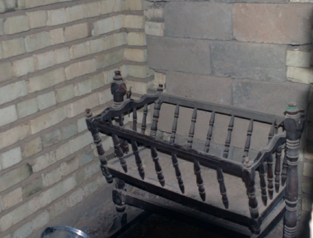 A baby crib collects dust in a little room.