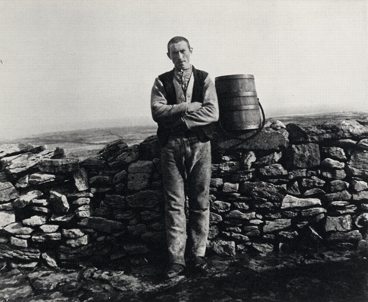 Grayscale Portrait Photo of John Millington Synge standing by a stone wall