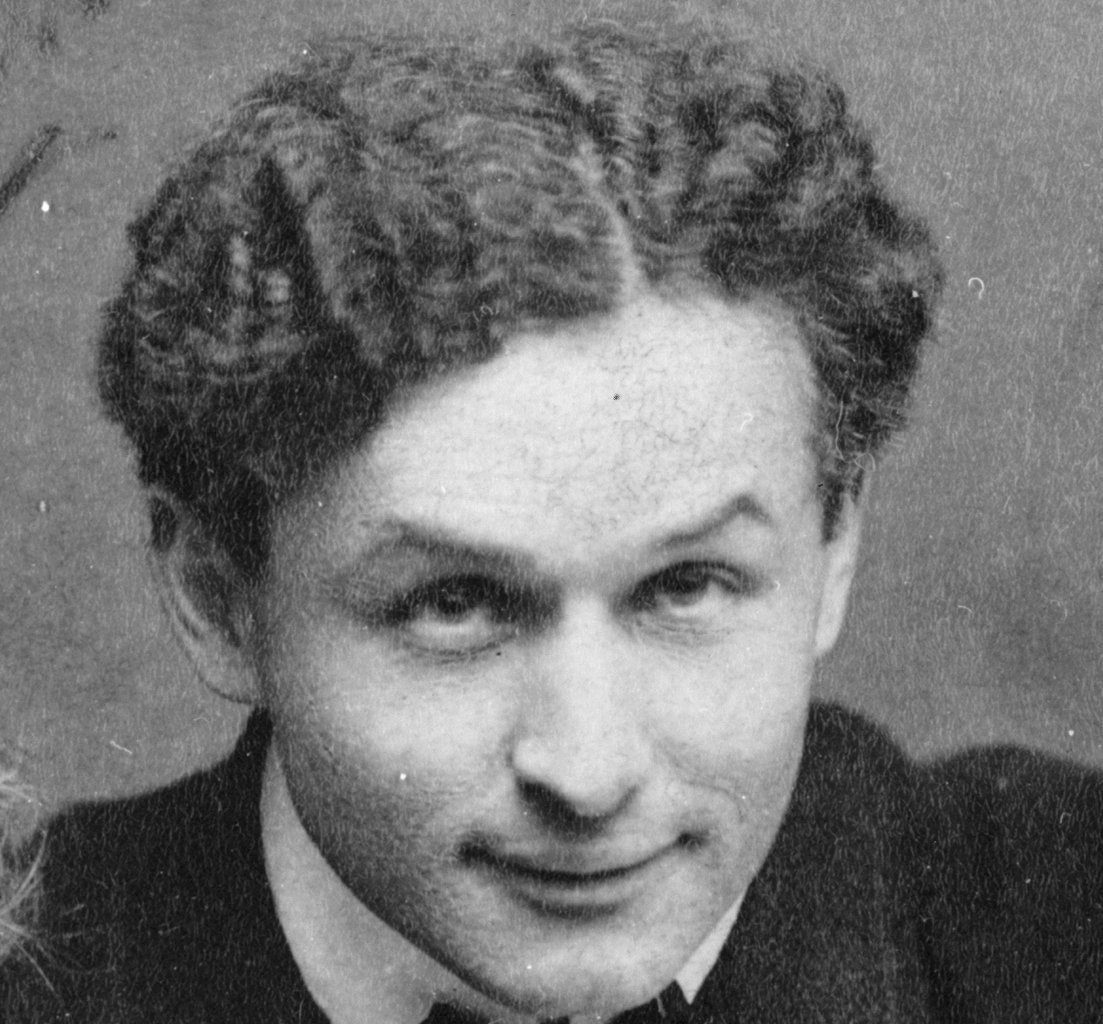 Grayscale Portrait Photo of Harry Houdini in a dark suit, smiling, facing the camera
