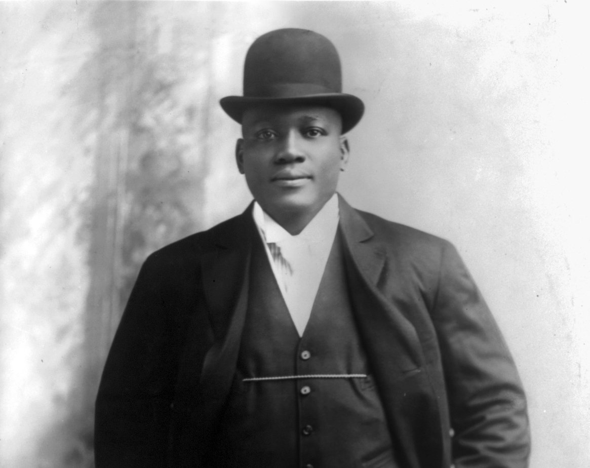 Grayscale Portrait Photo of the American heavyweight boxer Jack Johnson in a dak suit