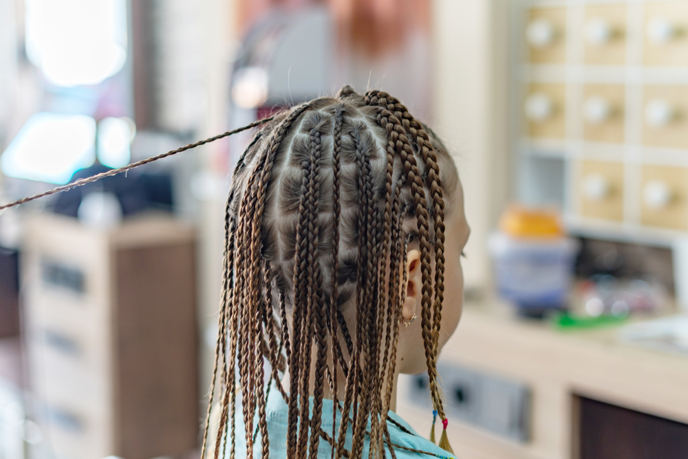 braiding a lot of braids for girl in the beauty salon