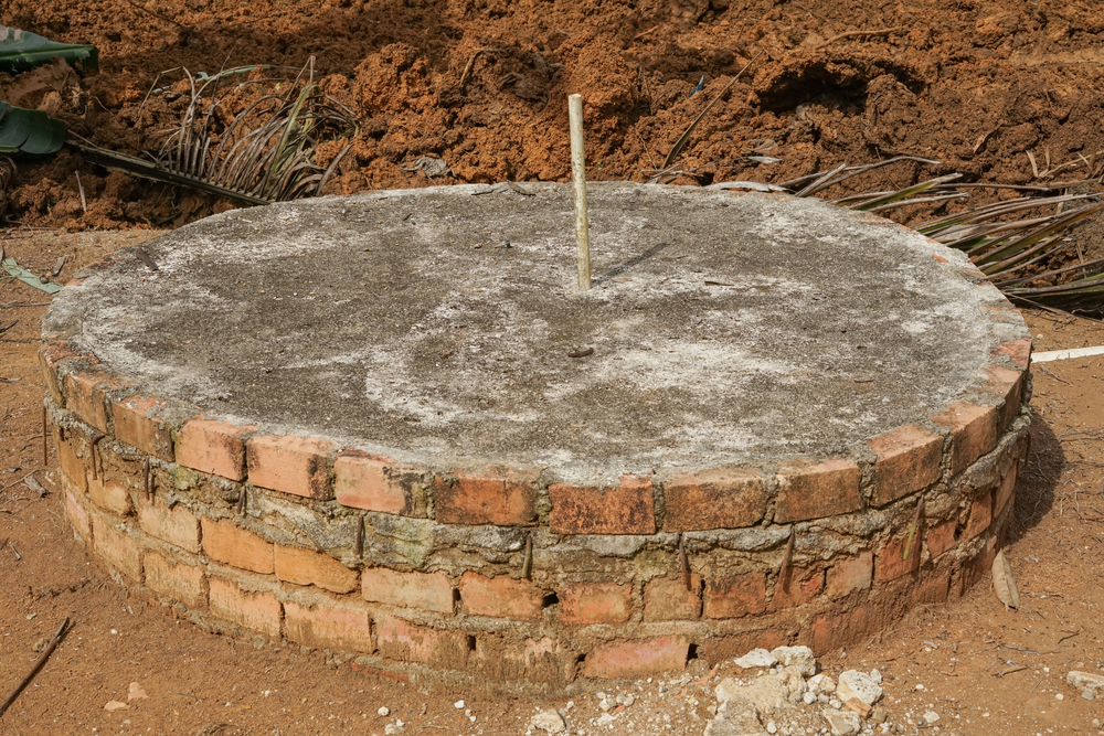 A simple circular septic tank made of red bricks and cement