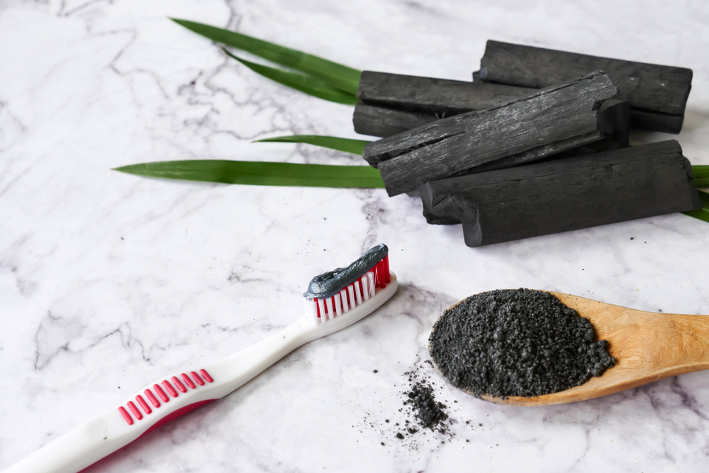 Toothpaste by activated charcoal powder on marble table