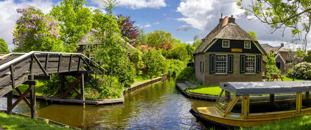 Traditional thatched roof home, tourist boat