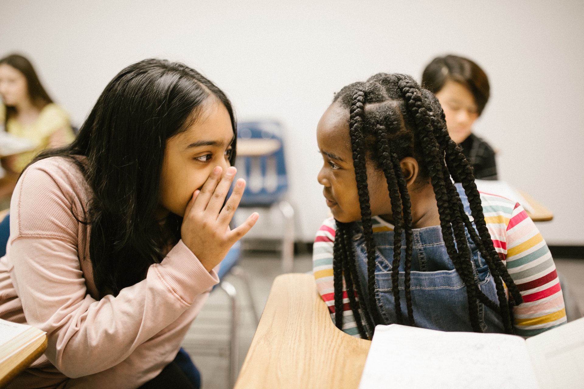 two girls gossiping with one another at school