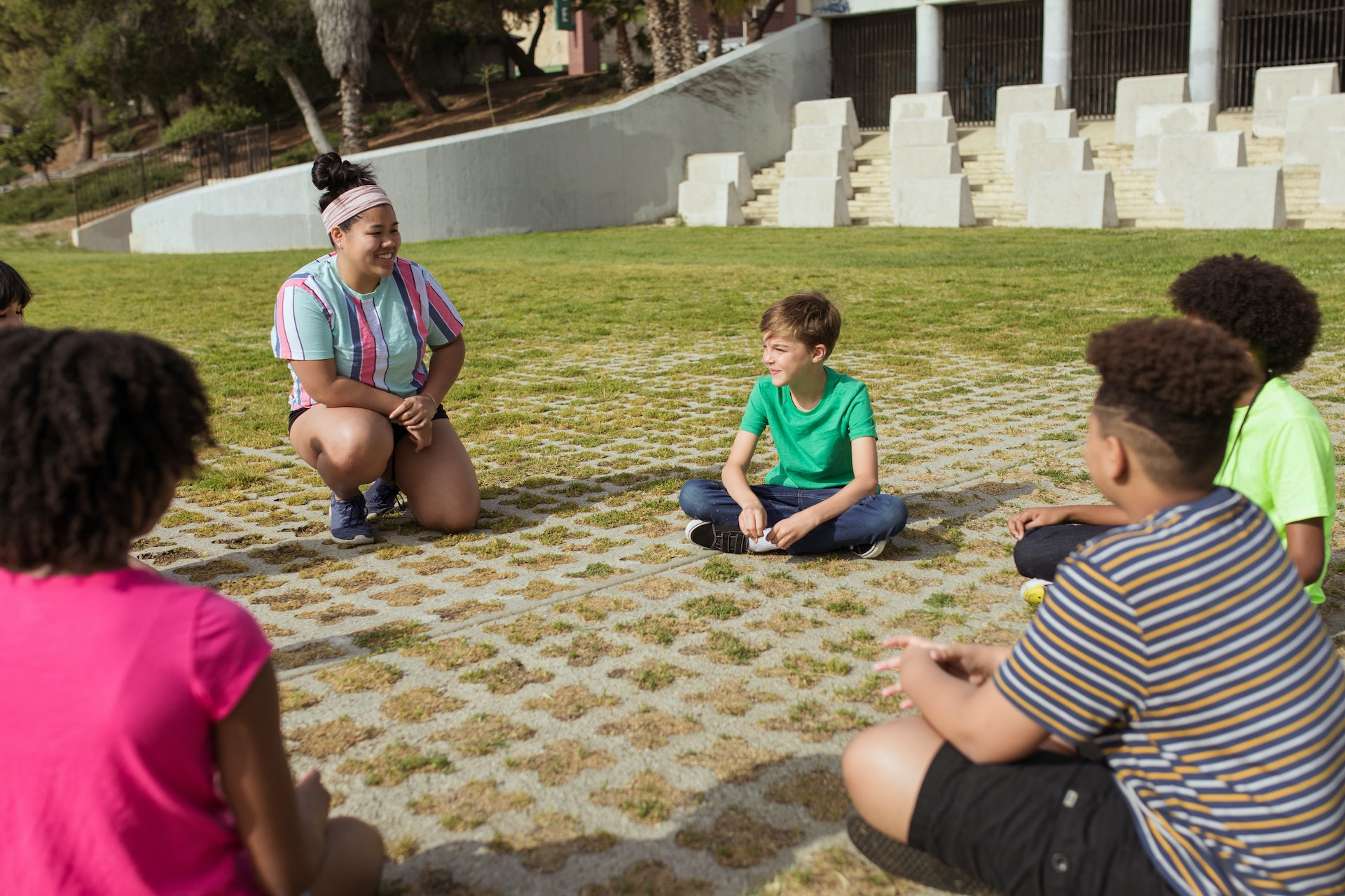 camp counselor sitting on a grass with kids