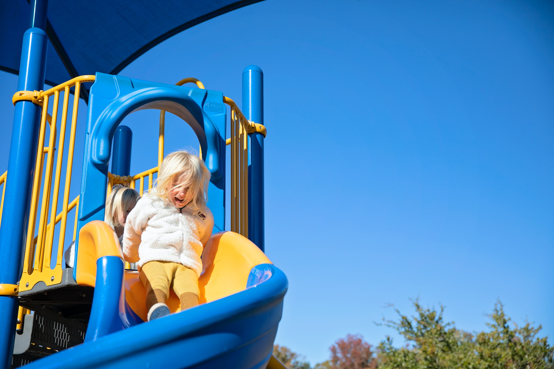 blond girl riding blue plastic slide