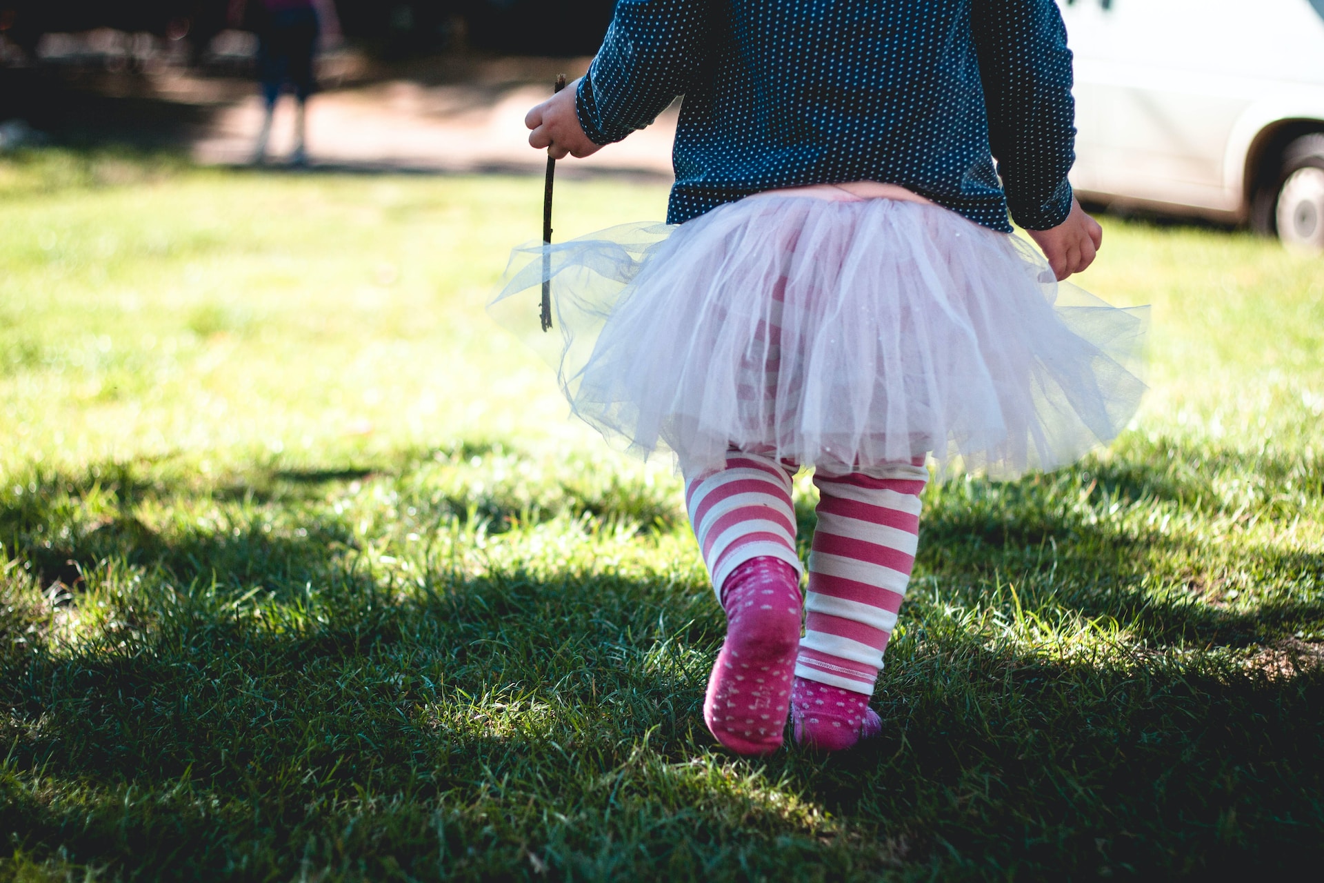 toddler girl walking on green grass at front yard