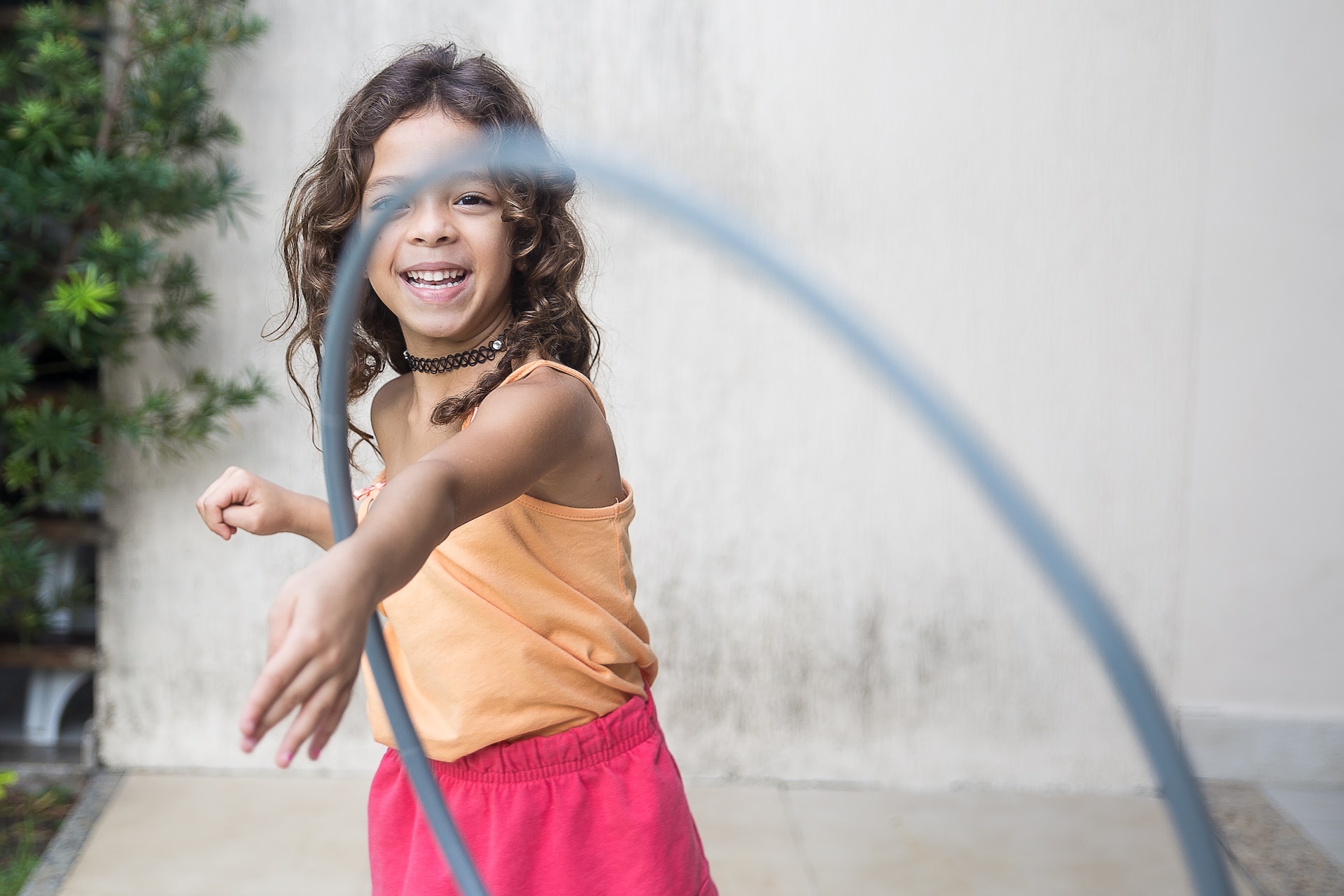 Girl playing hula hoop on her arm in front yard