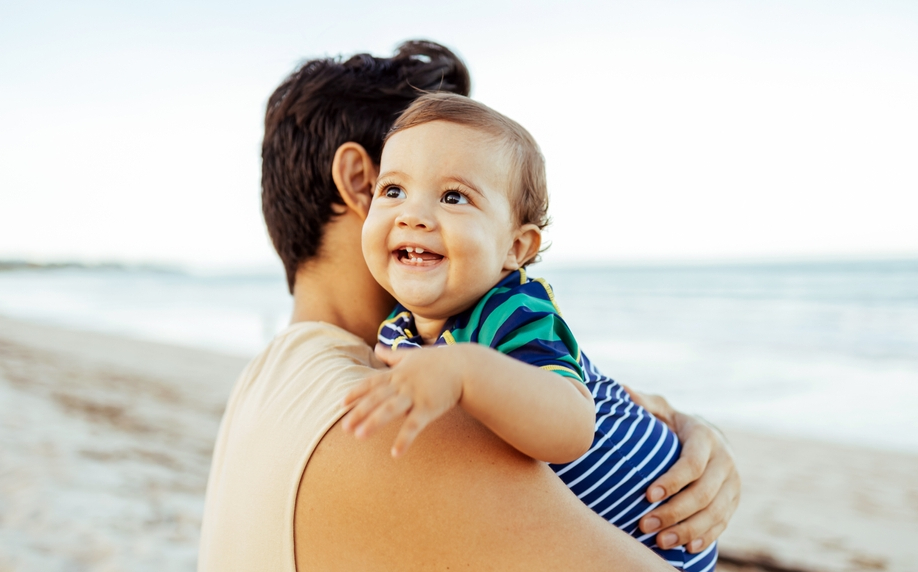 A young father and his baby son at the beach