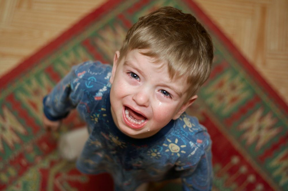 Crying little boy in blue pajamas