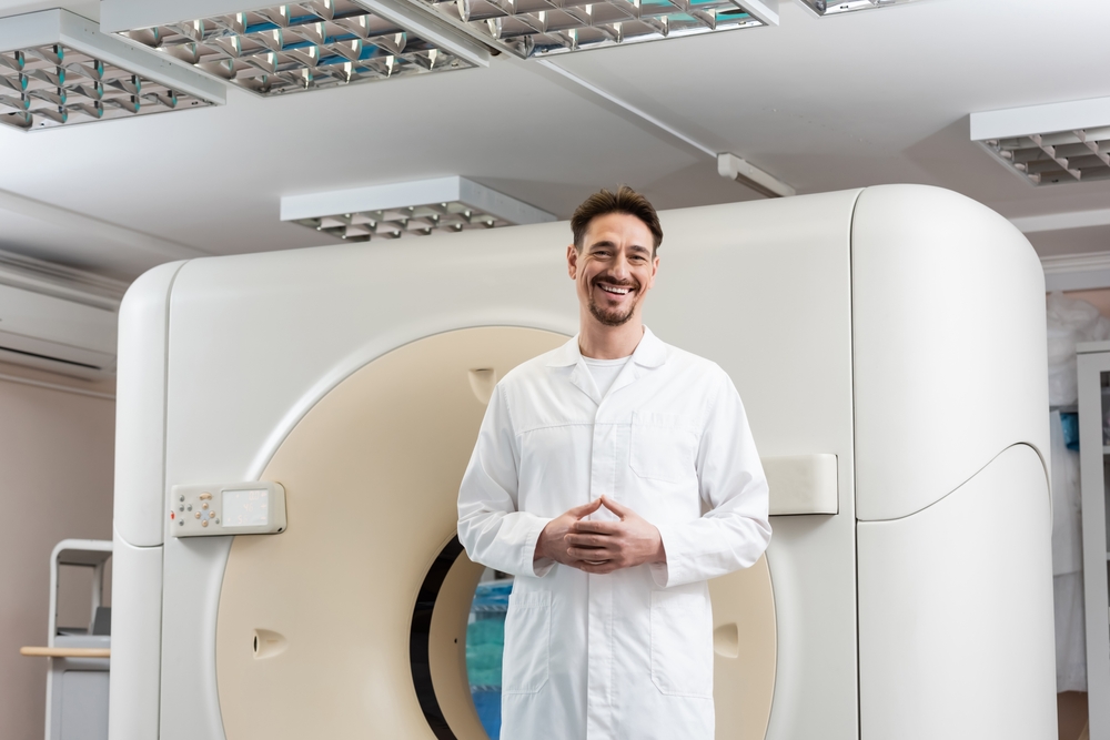 happy radiologist  standing near computed tomography scanner