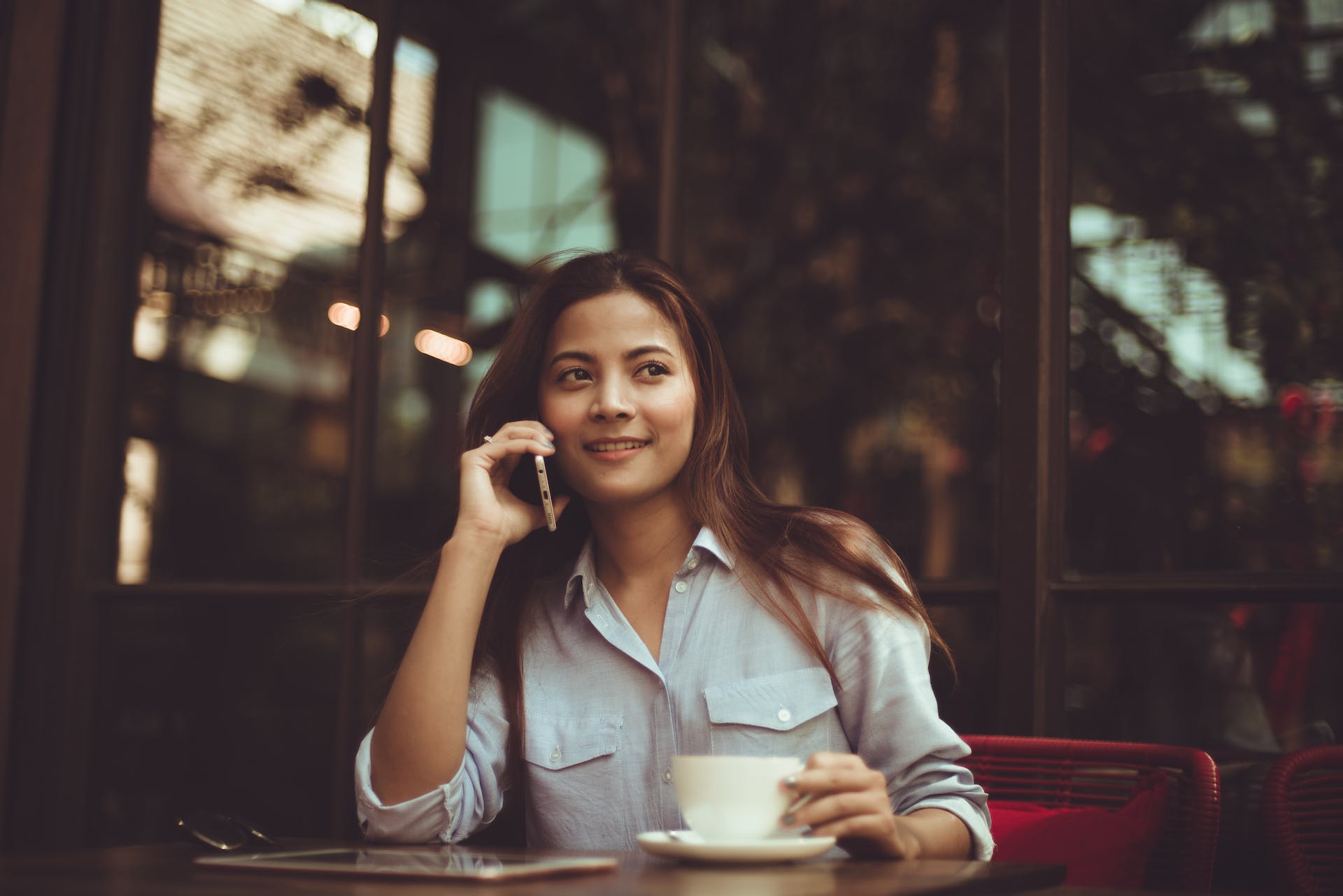 portrait of young woman using mobile phone in café